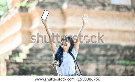 Traveler woman funny moment and showing her smartphone isolated screen in ancient travel location.