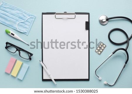 Overhead view healthcare accessories near clipboard with plank paper and spectacles on background