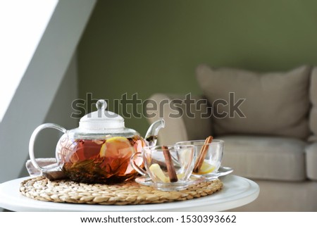 Cups and teapot with hot beverage on table in room