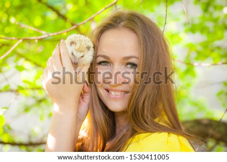 The concept of joy. Beautiful girl hugs a hedgehog. Woman in a yellow dress with a hedgehog in her arms. People and pets.