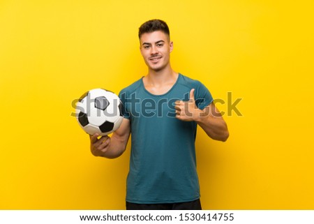 Handsome young football player man over isolated yellow background with thumbs up because something good has happened