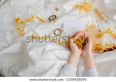 Bright festive golden confetti star sparkles woman hand on white background. Creative conceptual Christmas holiday birthday party top view 