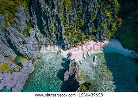 El Nido, Palawan, Philippines. Aerial view of Secret hidden lagoon beach with tourist banca boats on island hopping tour surrounded by karst cliffs scenery Royalty-Free Stock Photo #1530439658