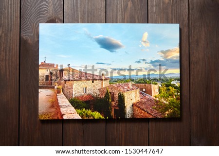 Canvas photo print on brown wooden background. Front view of colorful photography printed on glossy synthetic canvas. Photo hanging on a wall
