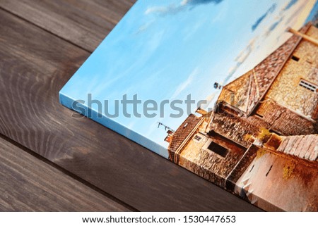 Canvas photo print on brown wooden background. Side view of colorful photography with gallery wrap. Photo printed on glossy canvas closeup