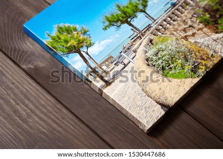 Canvas photo print on brown wooden background. Sample of gallery wrapping method of canvas stretching on stretcher bar. Side view of colorful photography closeup