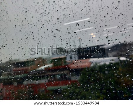 Background rain on the glass. Rain drops on window glasses surface with cloudy background .Urban view of rain drops falls on a window during a stormy day overlooking. Rain drops on the dirty glass.