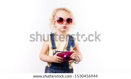 Little girl in pink sunglasses and a pink baby camera.