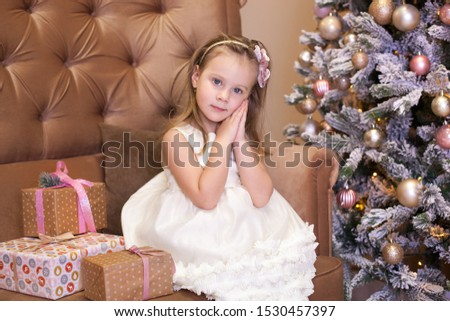 Merry Christmas, happy holidays! New Year 2021. Happy little girl with christmas present at home. child opens gift for new year in cozy living room in winter. child sits by Christmas tree with present