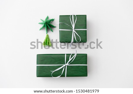 winter holidays, new year and celebration concept - gift boxes wrapped into green paper and origami christmas trees on white background