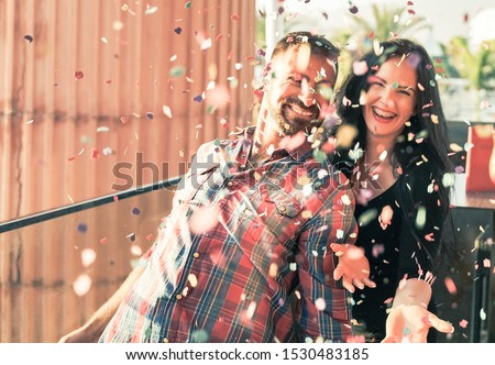 Millennials young people having fun celebrating in the discoteque. Happy couple doing party throwing confetti in the outdoor. Entertainment and festive holidays concept - Image