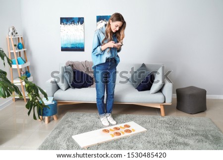Female food photographer with mobile phone taking picture of tasty cookies and orange slices at home