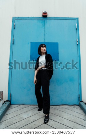 Black and white woman standing in front of the light blue door with dark blue paper.