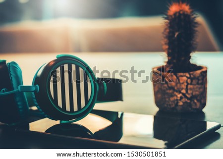 Abstract music listen, the sound of life, Headphone and mobile phone in wooden desk at home and yellow light background, vintage style. song relaxing in the cafe. 