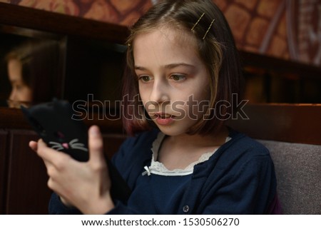 Blogger little girl makes video for her page.A schoolgirl is sitting after school in a cafe on the phone.A 9-year-old schoolgirl takes photo and videos for her pages on social networks.Popular blogger
