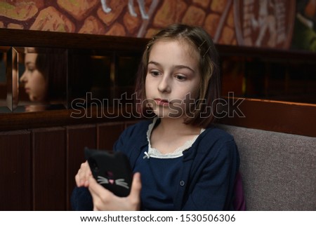 Blogger little girl makes video for her page.A schoolgirl is sitting after school in a cafe on the phone.A 9-year-old schoolgirl takes photo and videos for her pages on social networks.Popular blogger