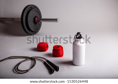 Training equipment: weights, water bottle, rope and hand bands. Sport accessories, grey background