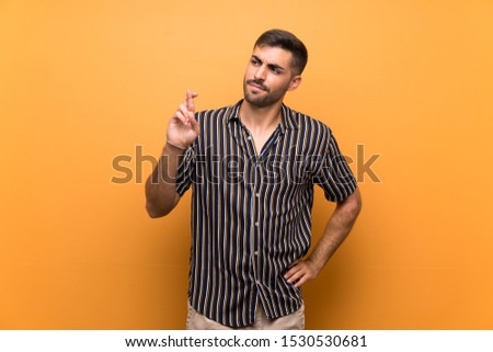 Handsome man with beard over isolated background with fingers crossing and wishing the best