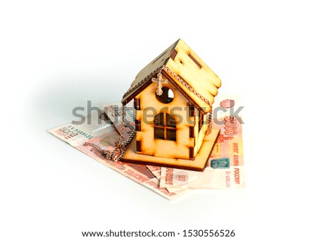 wooden house on banknotes Russian ruble and a gold chain with a cross as a symbol of protection of savings