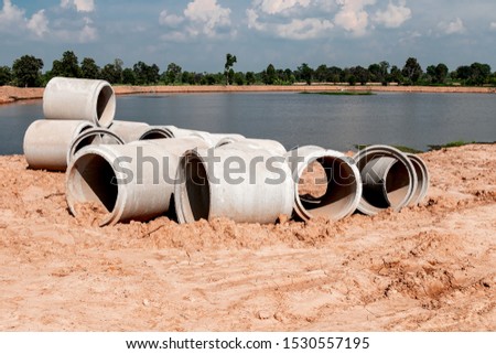 Large cement pipes on the ground to wait for installation under the soil. Riverside in the countryside of Thailand.