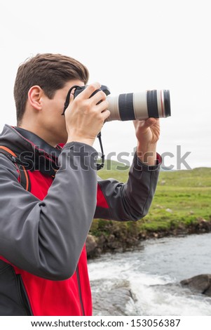 Brunette man on a hike taking a photograph in the countryside