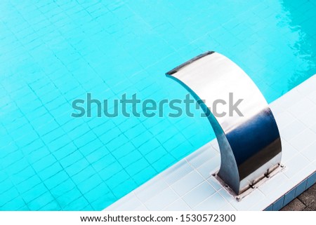 Blue swimming pool with a modern water flowon massage tap on a beautiful summer afternoon for background, high resolution