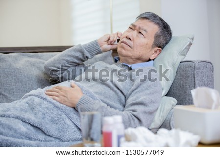 asian eldely man get sick and fever with thermometer lying on the sofa at home Royalty-Free Stock Photo #1530577049