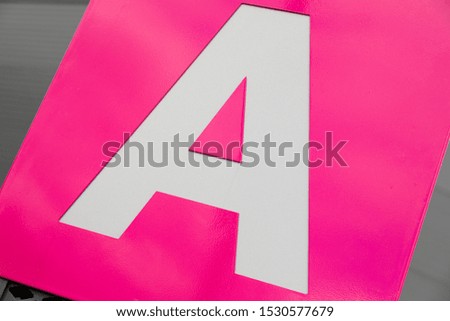 Close-up of white letter A on pink background