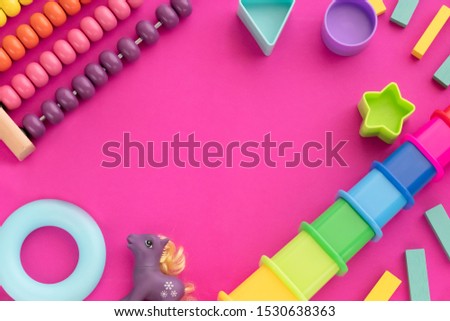 Top view children educational games, frame kids toys purple paper background. Wooden cubes, stars, circles, pyramid, horse, abacus, frog. Flat lay, copy space Royalty-Free Stock Photo #1530638363