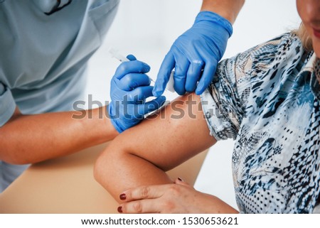 Close up view of female doctor that injecting patient in the clinic by syringe.