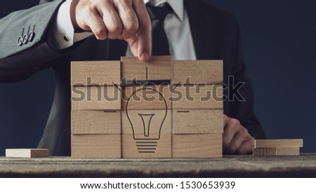 Conceptual image of business vision and idea - businessman assembling a light bulb of wooden pegs.