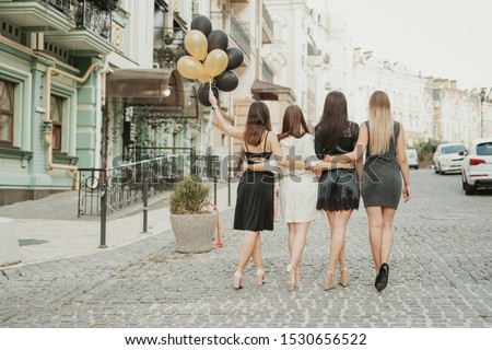 bachelorette party outdoor photoshoot. girls in black mini dresses. girls with balloons. happy beautiful girlfriends with balloons having a great time at the hen party