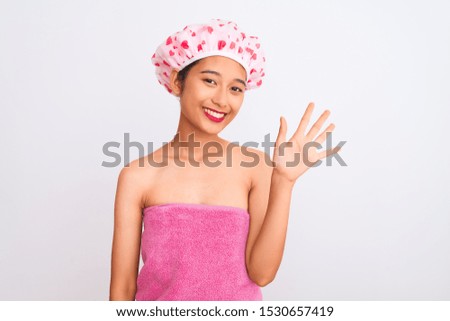 Young chinese woman wearing shower towel and cap bath over isolated white background showing and pointing up with fingers number five while smiling confident and happy.