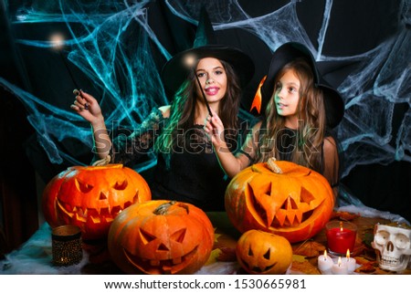Happy Halloween . Beautiful caucasian mother and her daughter in witch costumes enjoy using magic with magic wand