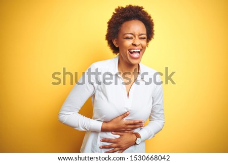 African american business woman over isolated yellow background smiling and laughing hard out loud because funny crazy joke with hands on body.