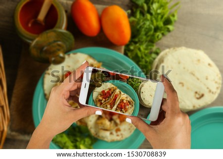 Food photography with a smartphone.   Woman Hands taking a photo of a food plate (tacos).