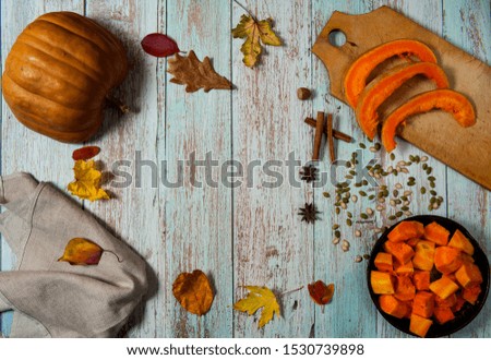Cooking pumpkin for baking. Half a peeled pumpkin, slices on a cutting Board, spices, pieces in bowl, linen napkin, seeds, autumn leaves on a light blue wooden background.