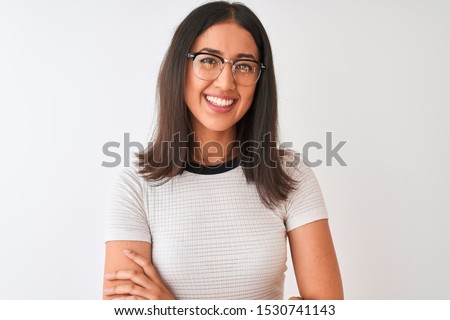 Chinese woman wearing casual t-shirt and glasses standing over isolated white background happy face smiling with crossed arms looking at the camera. Positive person.