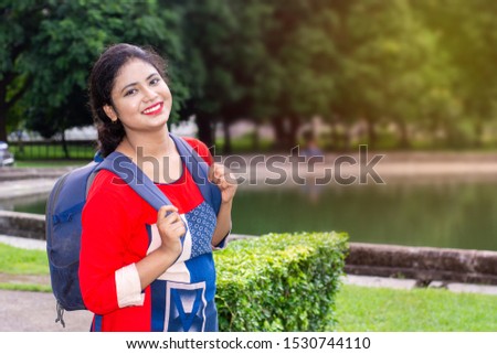 Indian woman carrying blue color travelling or school bag with a beautiful smile on face