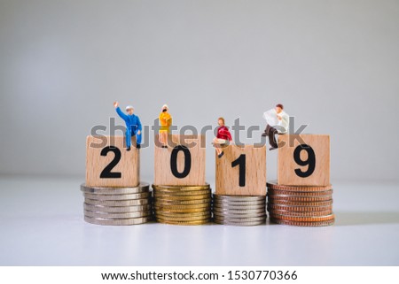 Miniature people, business team on wooden block year 2019 and stack coins using as business and financial concept