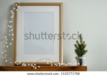 Christmas decorations in bright shiny colors with Christmas lights, picture frames with blurred white wall background.