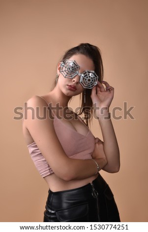 girls wearing glasses. Halloween concept.A girl of 18-20 years old wore glasses with a spider design for Halloween or a theme party.A series of photos of a girl in a studio on a beige background