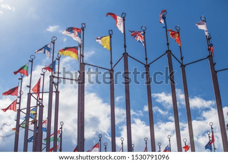 Flags of European states on flagpoles against the background of a cloudy sky.