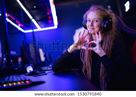 Streamer beautiful girl shows heart sign with hands professional gamer playing online games computer, neon color. Royalty-Free Stock Photo #1530791840