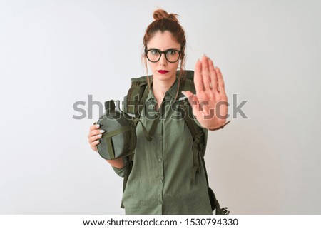 Redhead hiker woman wearing backpack holding canteen over isolated white background with open hand doing stop sign with serious and confident expression, defense gesture