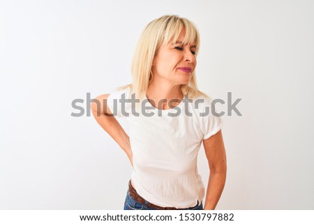 Middle age woman wearing casual t-shirt standing over isolated white background Suffering of backache, touching back with hand, muscular pain