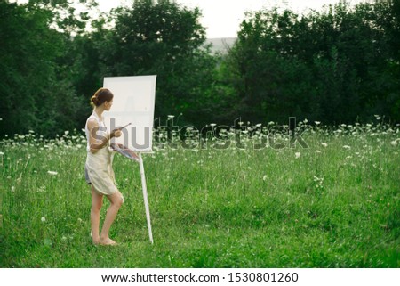 young woman in a forest paints a picture on canvas an easel