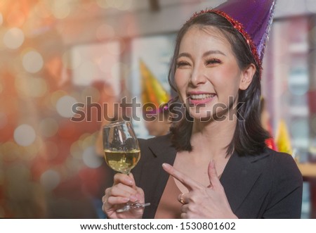 Businesswoman holding glass of white wine, having great time in the cooperate New Year party in the office.