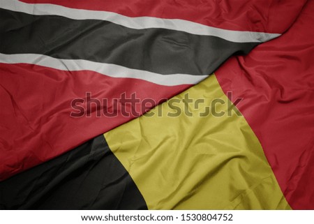 waving colorful flag of belgium and national flag of trinidad and tobago. macro
