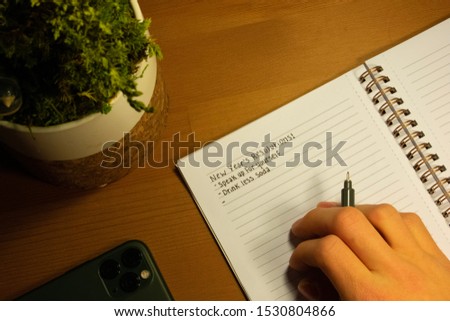Person writing a New Year’s Resolution List.